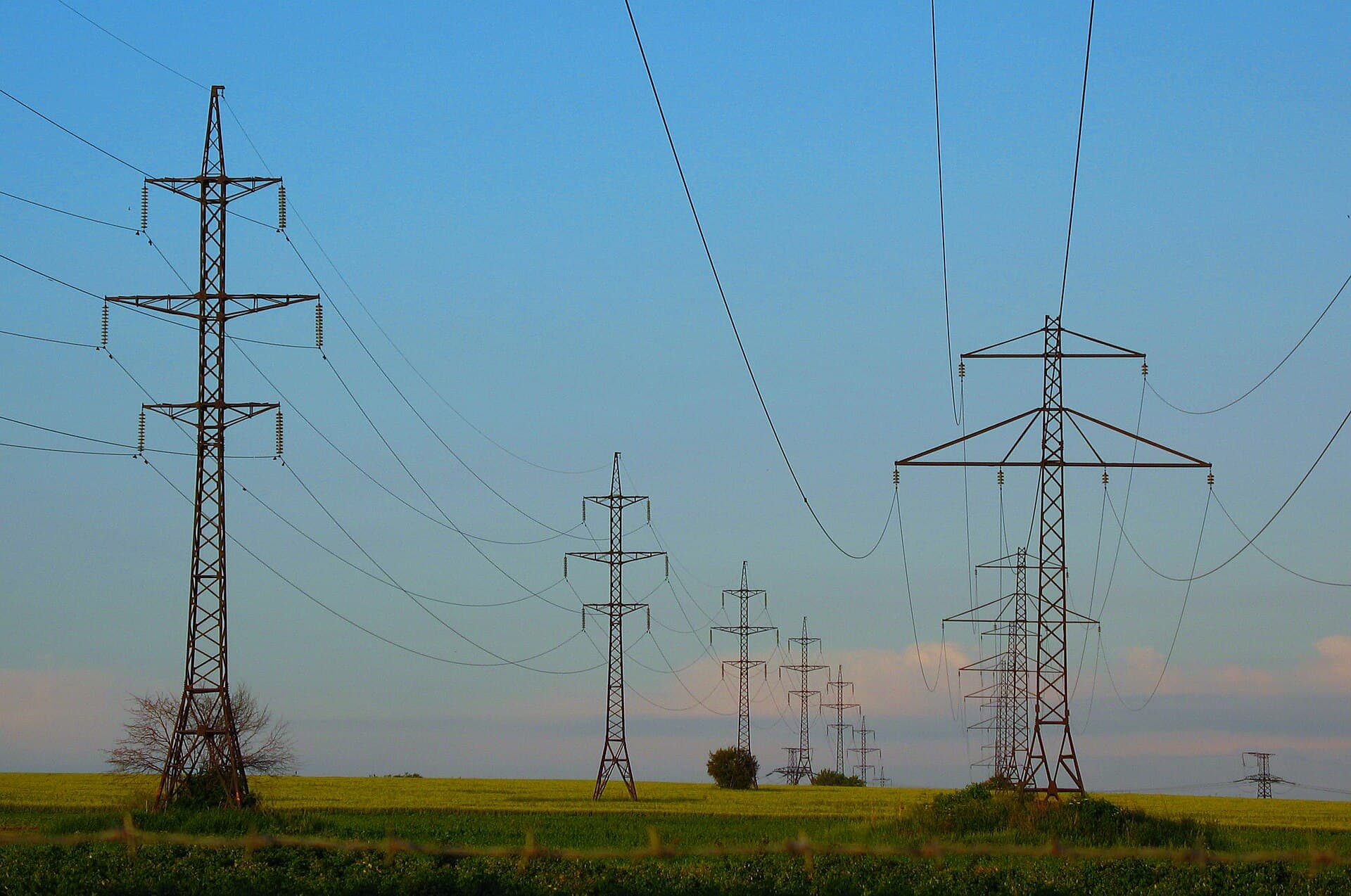 File de pylônes haute tension dans un paysage ouvert. Photographie d'illustration.